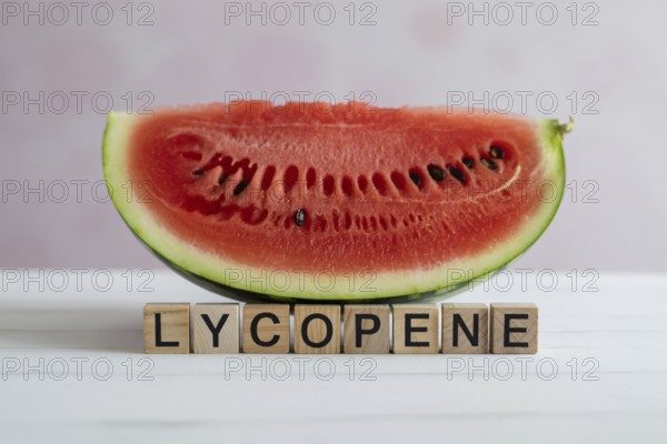 Watermelon slice with wooden blocks spelling Lycopene. Studio image emphasizing summer freshness and antioxidant content. Generative ai, AI generated
