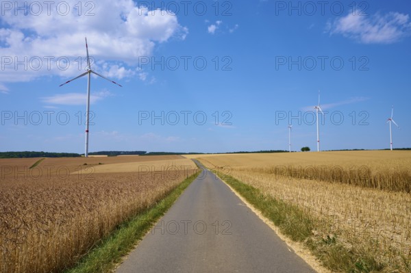 Several wind turbines above golden cornfields under a clear summer sky, summer, Retzstadt, Main Spessart district, Bavaria, Germany