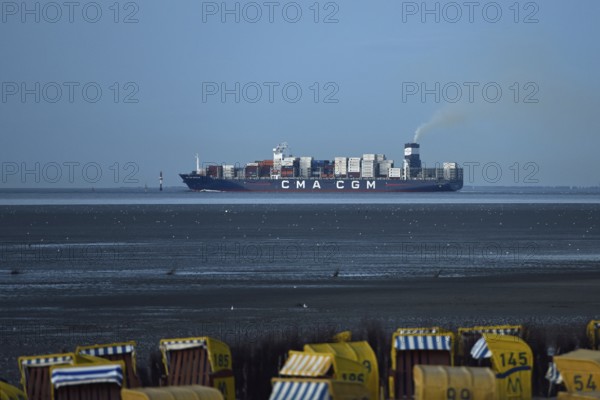 Large container ship... Elbe fairway through the Wadden Sea of the North Sea off Cuxhaven, view from Duhnen to the mouth of the Elbe, Lower Saxony, Germany, Western Europe. In the foreground you can see beach chairs where people want to enjoy their holidays