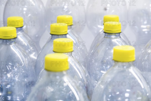 A collection of transparent plastic bottles with yellow screw caps