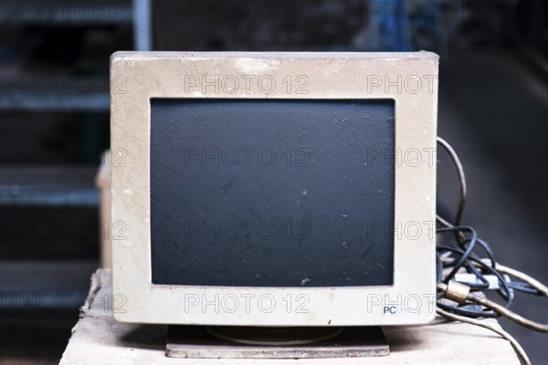 An old, dusty CRT monitor (cathode ray tube monitor) with a beige-grey housing. Significant signs of use and dust deposits are visible