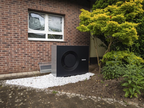 A black heat pump in a front garden in Hilden, Germany