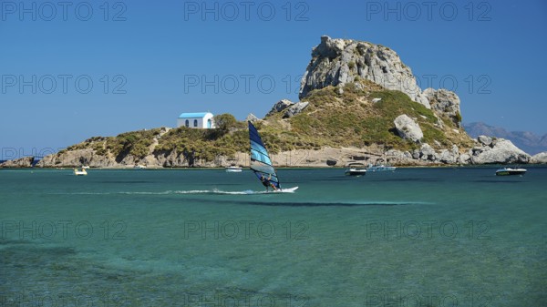 View of island with windsurfer and chapel in bright sunshine, Agios Stefanos Beach, Agios Stefanos Basilica, Chapel Agios Nikolaos, Kastri Island, Kos, Dodecanese, Greek Islands, Greece
