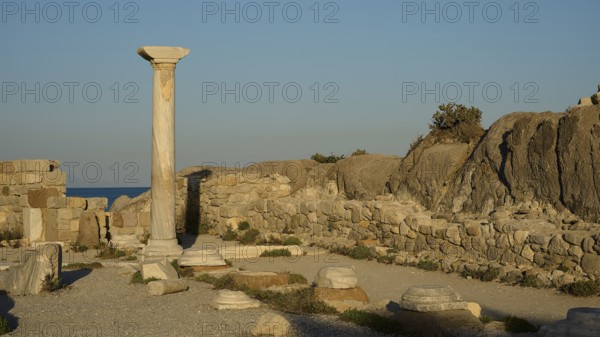 Ancient ruins with a standing stone column and surrounding rock structures in warm sunlight, Agios Stefanos Beach, Agios Stefanos Basilica, Agios Nikolaos Chapel, Kastri Island, Kos, Dodecanese, Greek Islands, Greece