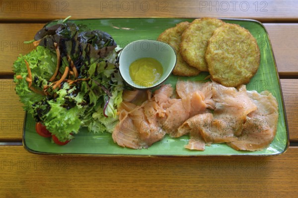 Salmon with baggers, potato pancakes and salad, served in a beer garden, Franconia, Bavaria, Germany