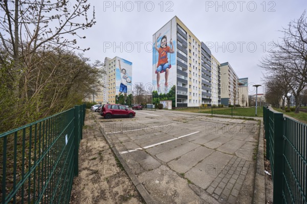 MWG-Wohnungsgenossenschaft eG Magdeburg, residential buildings, high-rise buildings, residential silos, car park, concrete slab road surface, metal fence, lantern, vehicles, diffuse light, cloudy, Lumumbastrasse, Magdeburg, state capital, independent city, Saxony-Anhalt, Germany