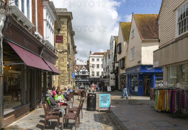 People sitting in street outside Reeve cafe bakery, Butcher Row, Salisbury, Wiltshire, England, UK