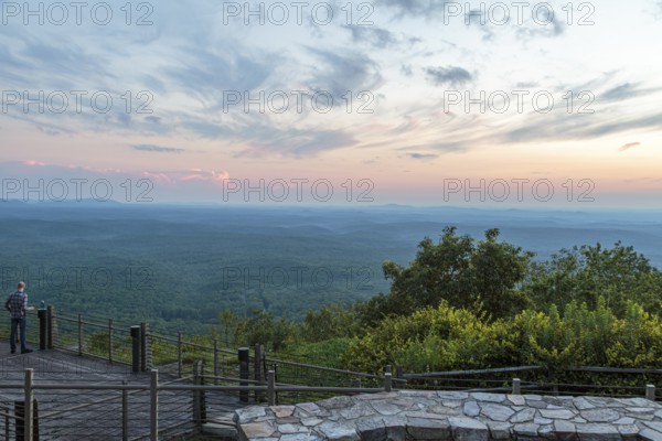 Man looking out over the valley at sunset from the Vista Cliffside Restaurant in Cheaha State Park near Delta, Alabama