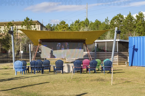 Big screen television under an awning at The Fort outdoor dining and entertainment hangout composed of repurposed shipping containers in Spanish Fort, Alabama, USA