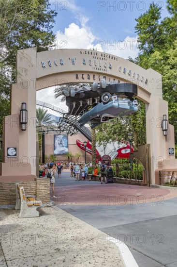 Masked park guests exiting under the entrance sign for the Rock 'n' Roller Coaster ride at Disney's Hollywood Studios theme park