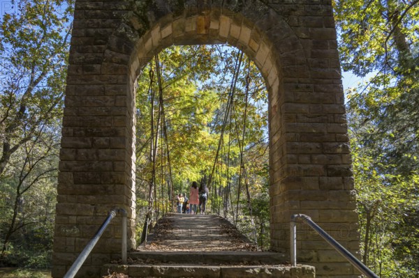 Park visitors walking across the Swinging bridge constructed in 1939 at Tishomingo State Park in northeast Mississippi