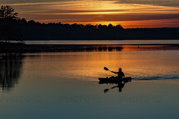 Man paddling his kayak at sunset on the lake at Little Black Creek campground near Lumberton, Mississippi