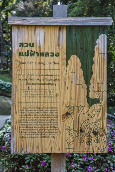 Wooden sign in Thai and English describes the Mae Fah Luang Garden inside the Doi Tung tourist attraction in Chiang Rai, Thailand