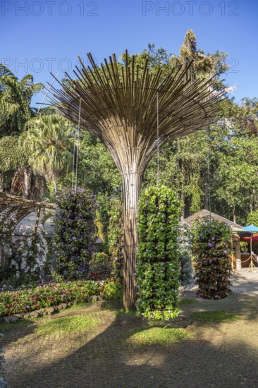 Fanned out column of bamboo holds hanging planters with colorful flowers at Mae Fah Luang Gardens within the Doi Tung tourist attraction in Chiang Rai, Thailand