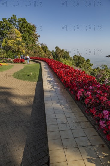 Colorful lush flower gardens line the perimeter of the mountain top Doi Tung Royal Villa lawn with a panoramic view of the surrounding land at the Doi Tung tourist attraction in Chiang Rai, Thailand