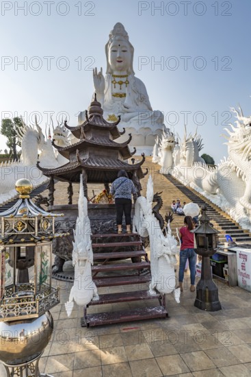 Visitors make a wai phra offering to Buddah in front of the Guan Yin (Goddess of Mercy) statue at Wat Huay Pla Kang Temple in Chiang Rai province of Northern Thailand