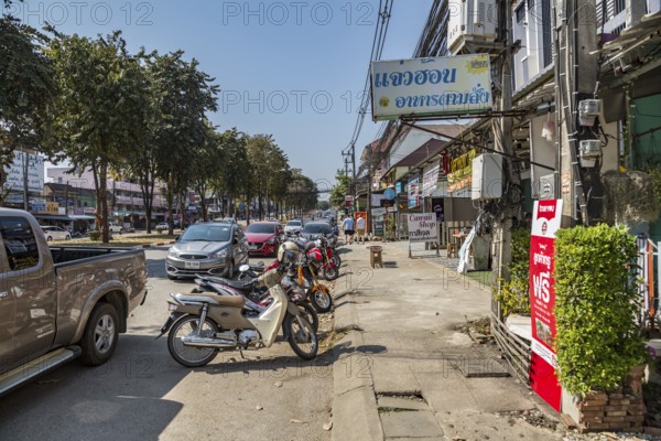 Cars and scooters double parked along Ban Du street in Chiang Rai, Thailand