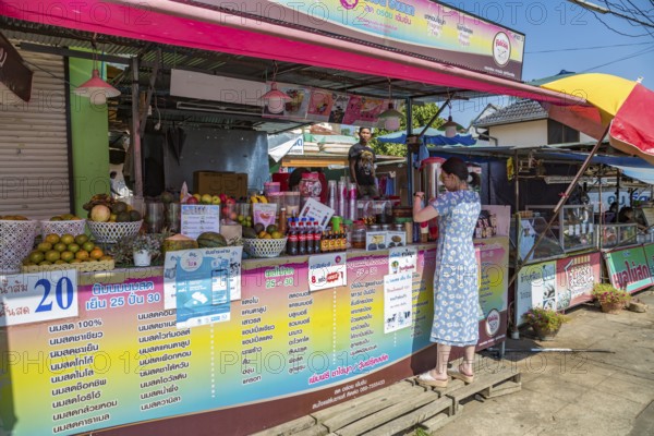 Thai woman shopping at a streetside drink stand in Chiang Rai province of Northern Thailand