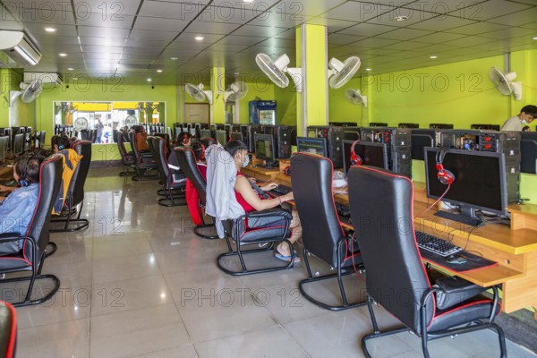 Thai men and boys playing games online at an Internet gaming business in Chiang Rai, Thailand