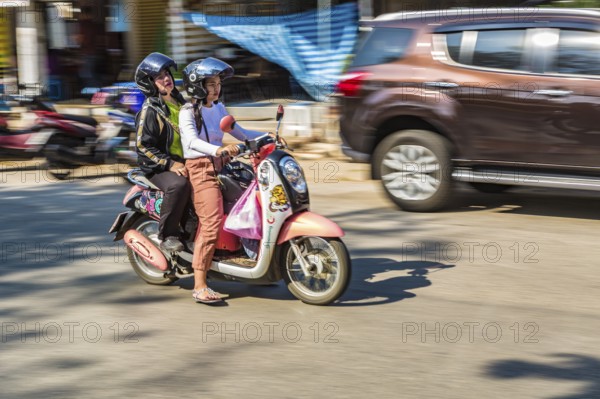 Thai women riding a scooter along Ban Du street in Chiang Rai, Thailand