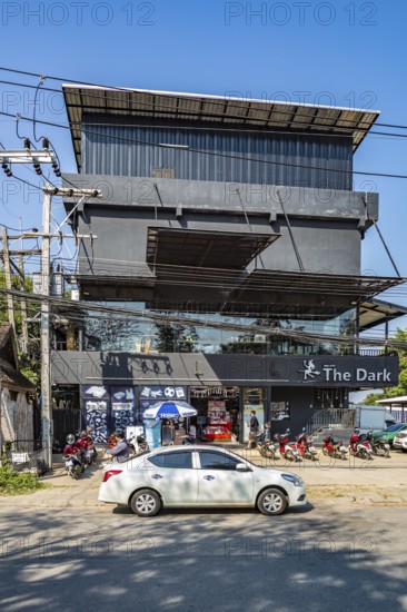 Scooters line the sidewalk outside The Dark restaurant in Shiang Rai, Thailand