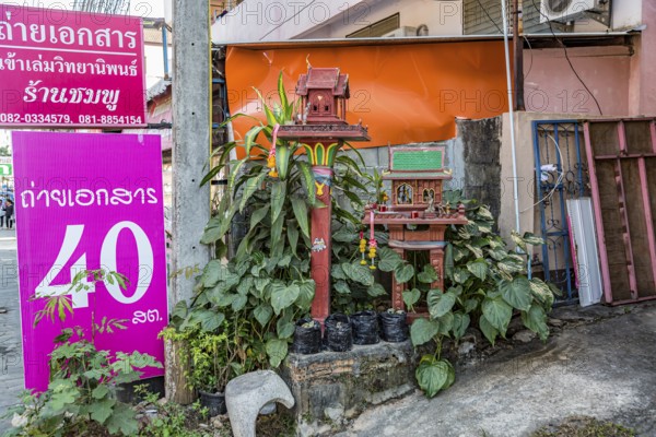 Buddahist shrine outside of a business on the sidewalk in Chiang Rai province of Northern Thailand