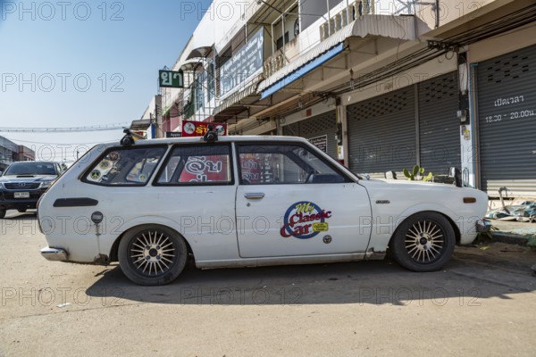 Classic 1976 Toyota Corolla station wagon with My Classic Car with Dennis Gage television program logo on door in urban area of Chiang Rai, Thailand