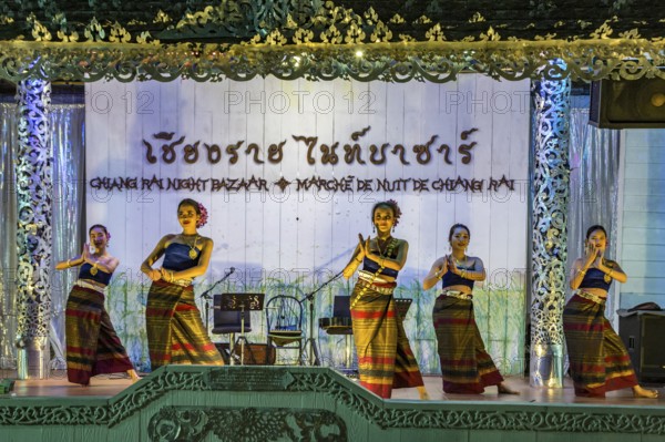 Traditional Thai dancers perform on a lighted stage at the night market in downtown Chiang Rai, Thailand