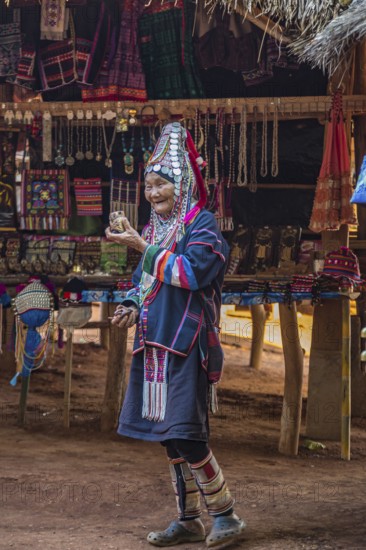 Elderly traditionally dressed woman selling art and craft items in the Akha tribe area of the Union of Hill Tribe Villages outside of Chiang Rai in the Nanglae District of Thailand