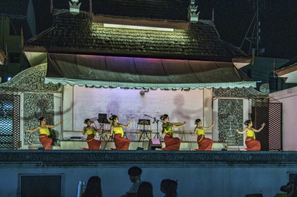 Traditional Thai dancers perform on a lighted stage at the night market in downtown Chiang Rai, Thailand