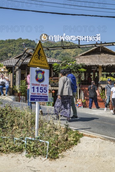 Sign encouraging tourists to call police if needed while visiting Pha Mi Village in Mae Sai district of Chiang Rai, Thailand
