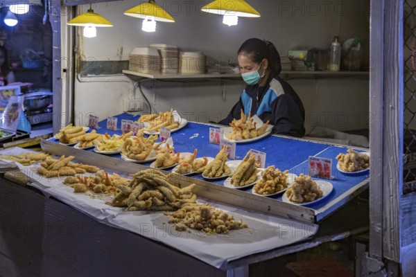 Thai street vendor offers fresh fried seafood at the night market in downtown Chiang Rai, Thailand