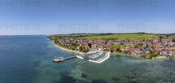 Luftbild, Panorama von der Bodenseegemeinde Hagnau, Winzerdorf und beliebter Ferienort am Bodensee, dahinter Rebhänge, auf denen hauptsächlich die Weinsorten Müller Thurgau und Blauer Burgunder angebaut werden. Am Seeufer der am 23.Mai 2025 eingeweihte, neue Westhafen, Yachthafen mit der Schiffanlegestelle, Bodenseekreis, Baden-Württemberg, Deutschland