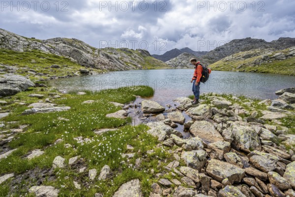 Mountaineer at a mountain lake in high mountain landscape at the Upper Senner Egete, Seven Lakes Hike, Stubai Alps, near Ridnaun, South Tyrol, Italy