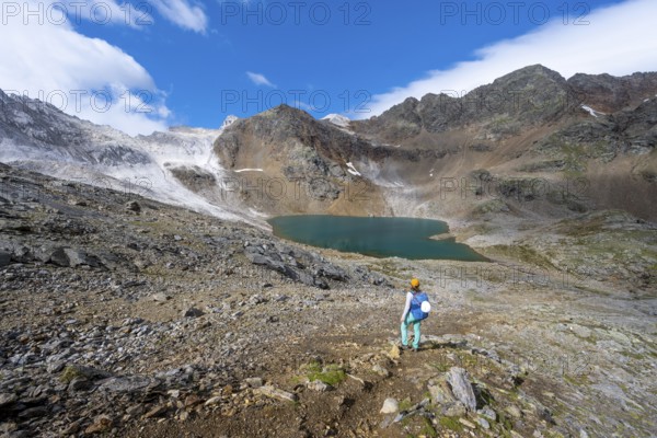 Mountaineer in front of mountain landscape with limestone rocks between granite mountains, mountain lake Hinterer Senner Egetsee and mountain peak of the Moarer Weißen, Seven Lakes Hike, Stubai Alps, near Ridnaun, South Tyrol, Italy