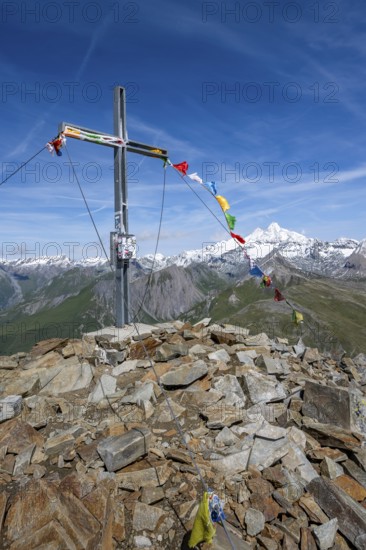 Böses Weibl summit with summit cross and colourful prayer flags, view of picturesque mountain landscape with snow-covered summit of the Großglockner, Wiener Höhenweg, Schober group, Hohe Tauern National Park, Carinthia, Austria