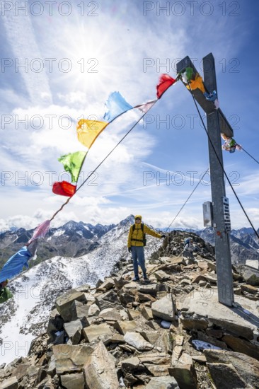 Mountaineers at the summit of Böses Weibl with summit cross and colourful prayer flags, view of picturesque mountain landscape with snow-covered peaks, Wiener Höhenweg, Schobergruppe, Hohe Tauern National Park, Carinthia, Austria