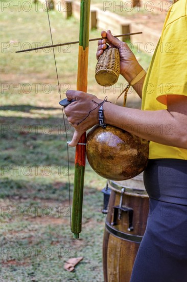 Woman playing an instrument of African origin called a berimbau outdoors, Minas Gerais, Brazil