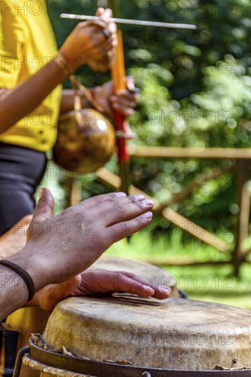 Hands of musicians playing berimbau and atabaque in Brazilian capoeira outdoors, Minas Gerais, Brazil