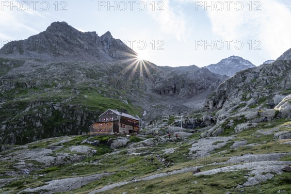 Mountain hut Elberfelderhütte in front of a rocky mountain landscape, sun star in the morning, in the upper Gössnitz valley, Wiener Höhenweg, Schober group, Hohe Tauern National Park, Carinthia, Austria