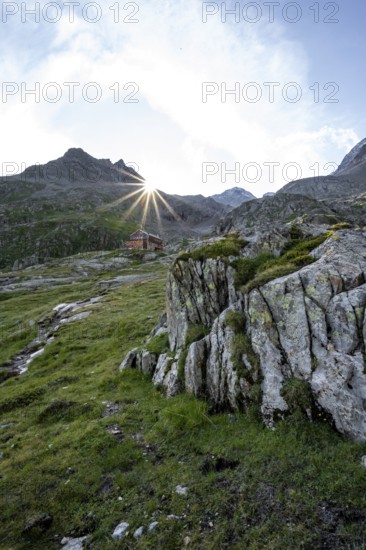 Mountain hut Elberfelderhütte in front of a rocky mountain landscape, sun star in the morning, in the upper Gössnitz valley, Wiener Höhenweg, Schober group, Hohe Tauern National Park, Carinthia, Austria