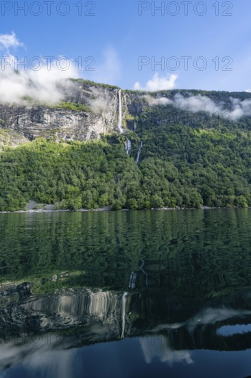 Atmospheric fjord landscape with Gjerdefossen waterfall, on the Geirangerfjord with reflection, Møre og Romsdal, Norway