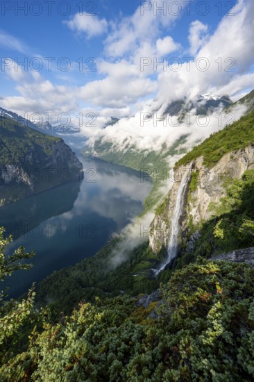 Gjerdefossen waterfall, at Ørnesvingen viewpoint, atmospheric clouds over the fjord in the morning light, at Geirangerfjord, near Geiranger, Møre og Romsdal, Norway