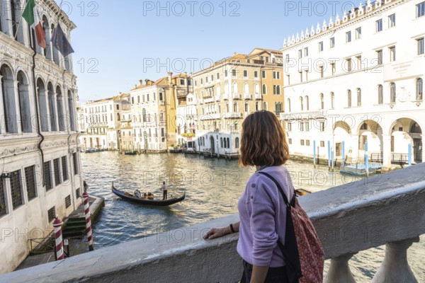 Young woman enjoying view of traditional gondola navigating grand canal amidst historic venetian buildings