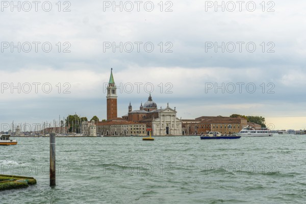 Scenic view featuring san giorgio maggiore church and its iconic bell tower, with boats sailing gracefully across the tranquil lagoon on a cloudy day