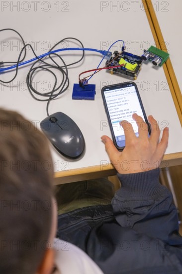 Child operating smartphone next to electronic devices on a table, Youth Research Centre Nagold, Germany