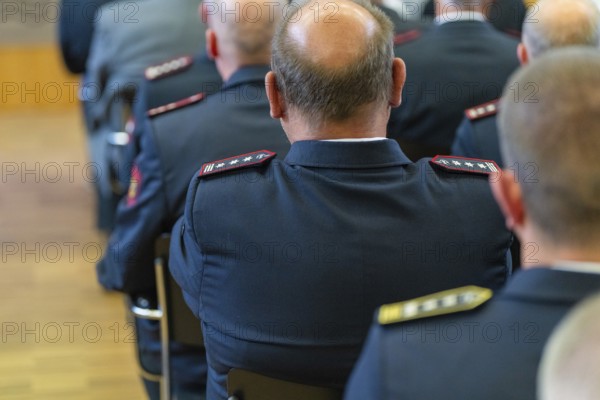 Rear view of men in uniforms sitting on chairs in a room