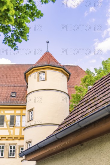 Historic tower in front of a blue sky with surrounding trees and half-timbered buildings, Deufringen, Aidlingen, Germany
