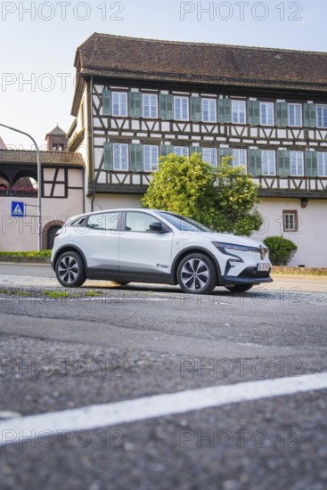 White car parked on an urban street in front of a large, traditional half-timbered house in summer, Renault Megane, Deer E Carsharing, electric car, Calw, Black Forest, Germany
