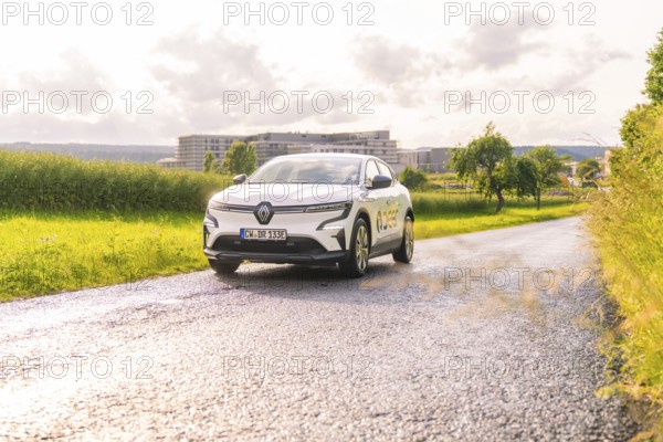White Renault car driving along a tarmac road in a vast landscape, Renault Megane, Deer E Carsharing, electric car, Calw, Black Forest, Germany